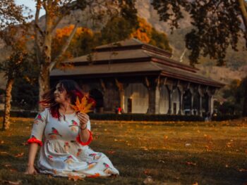 Woman in White and Red Floral Short-sleeved Dress Holding Maple Leaf